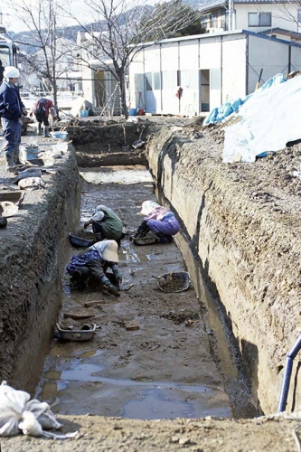 発掘作業員がスコップなどの道具を使って遺構の中に埋まった土を掘っている様子